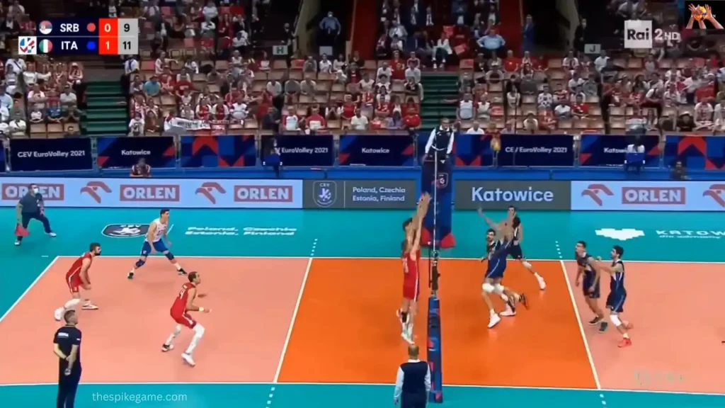 Volleyball attacker jumping to spike against two blockers during a match