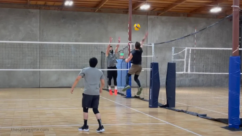 Volleyball player practicing a spike against a single blocker in an indoor gym